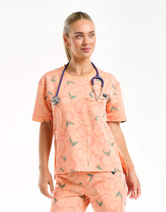 front view with stethoscope of peach crewneck scrub top