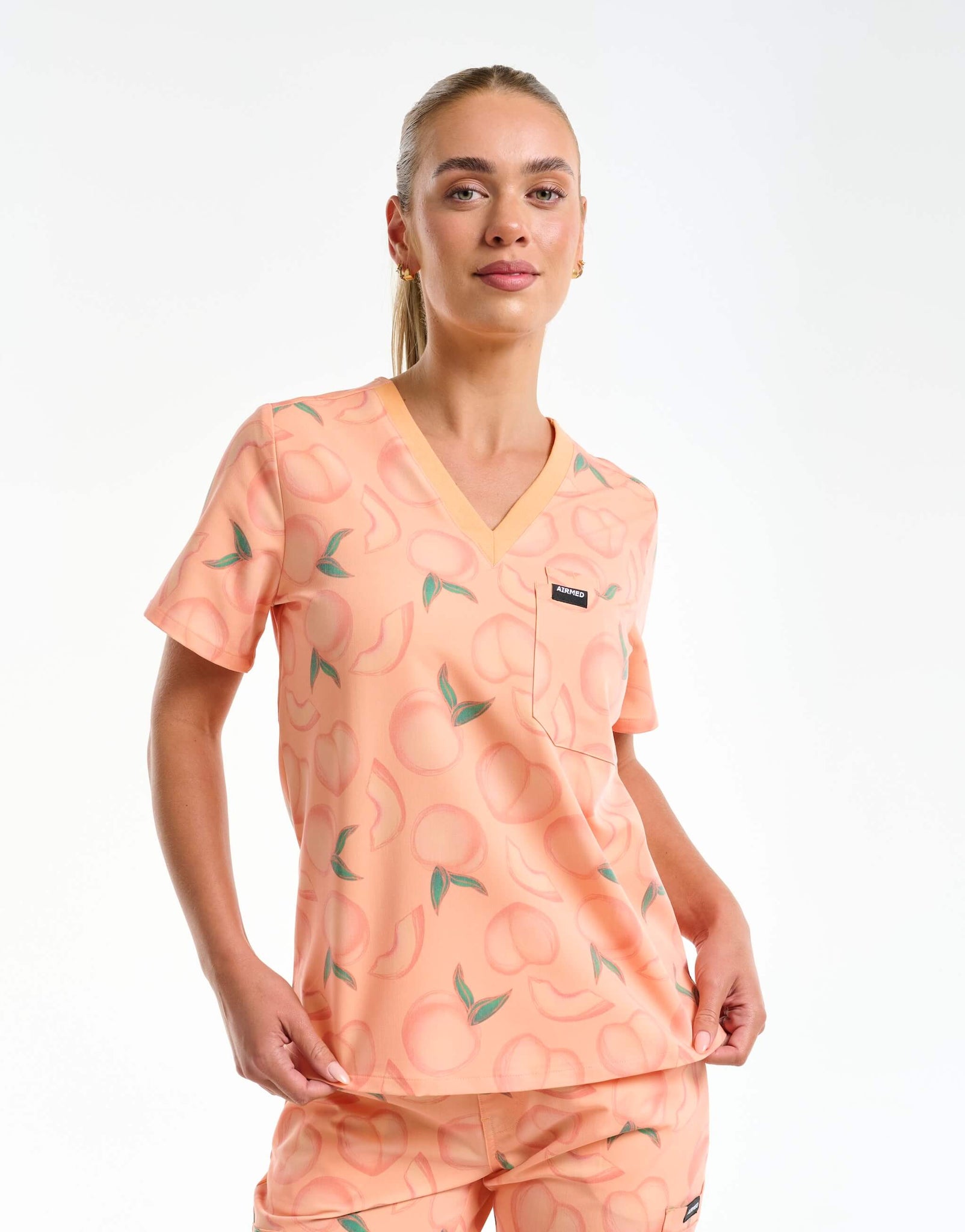 front view of peach one pocket v neck scrub top