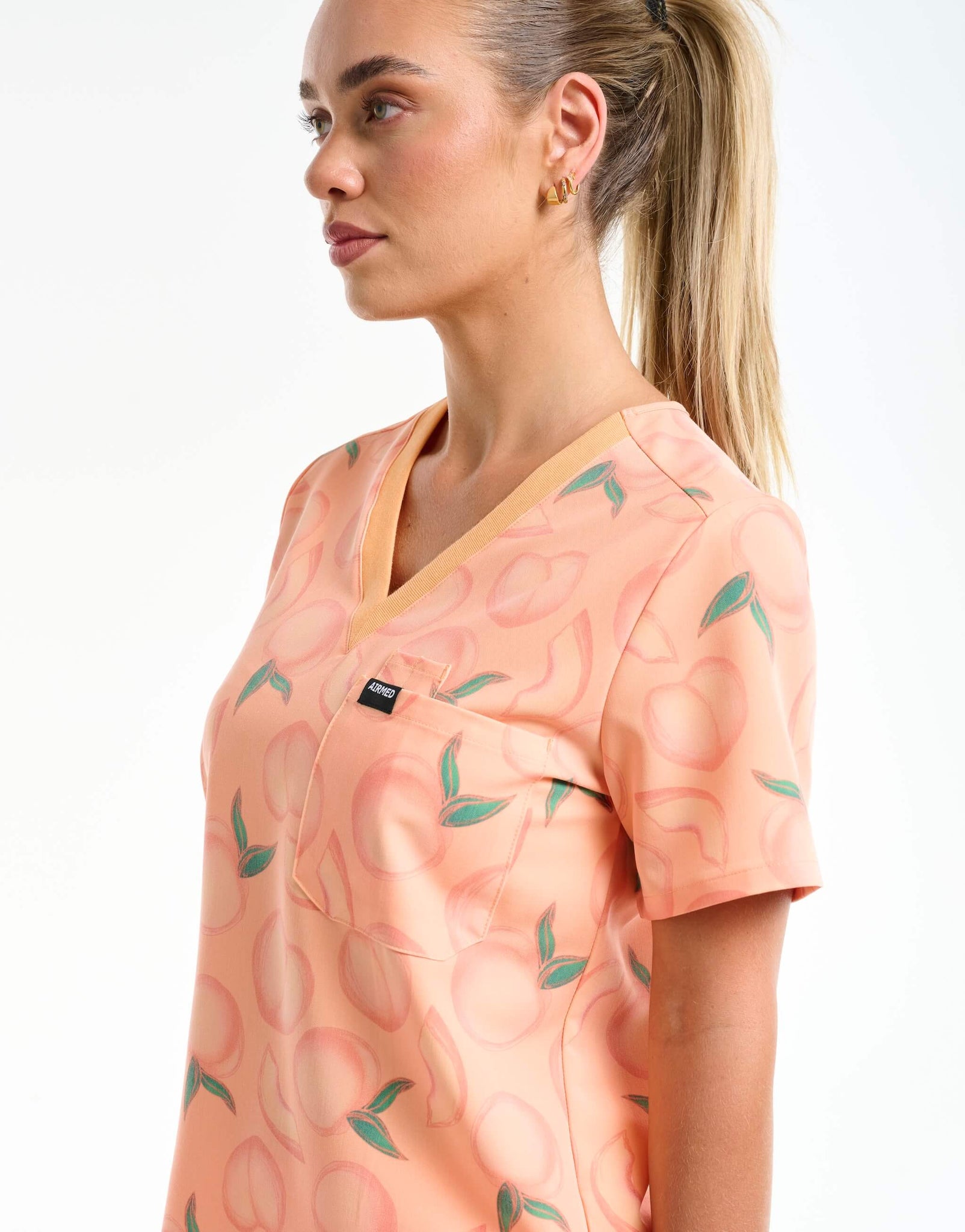 close up of neckline detail of peach one pocket v neck scrub top