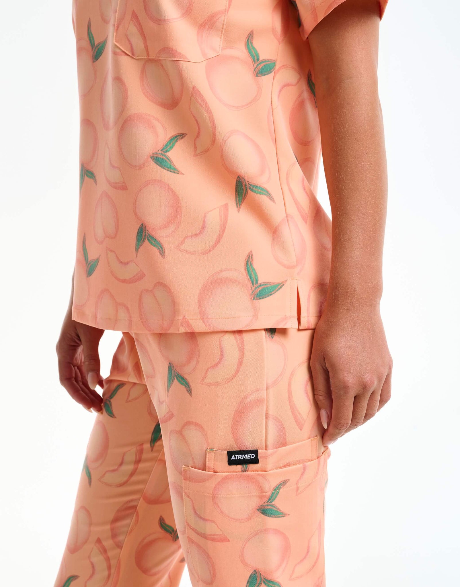 close up of hem detail of peach one pocket v neck scrub top
