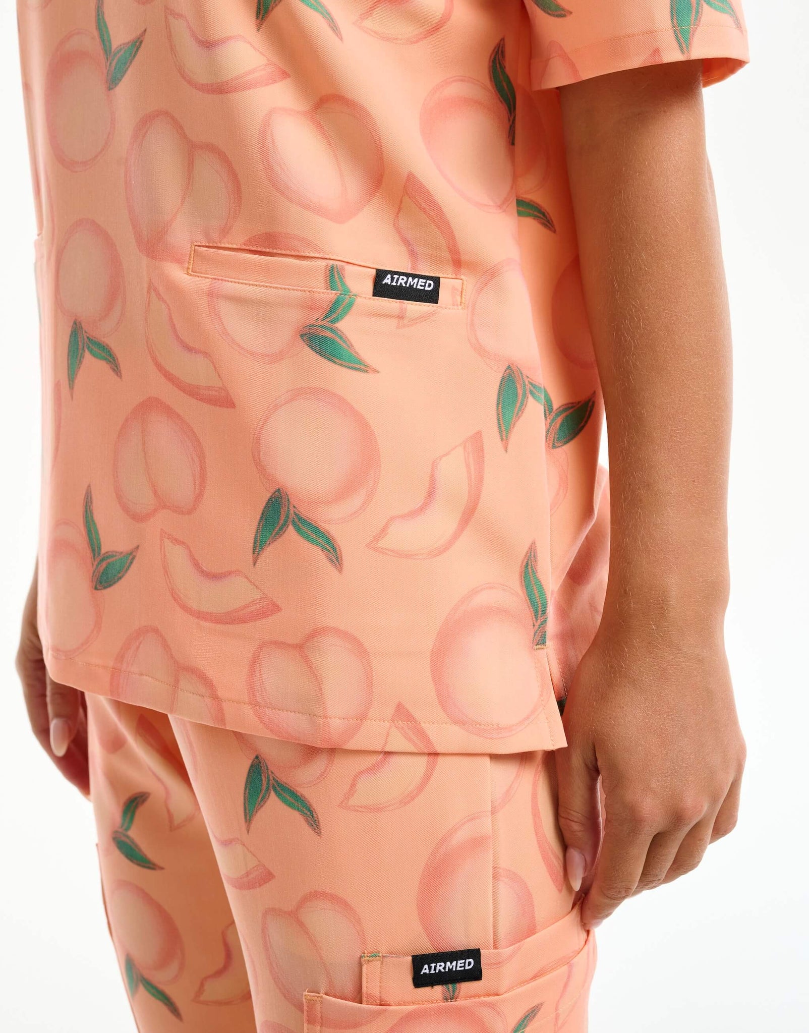 close up of hem detail of peach v neck scrub top